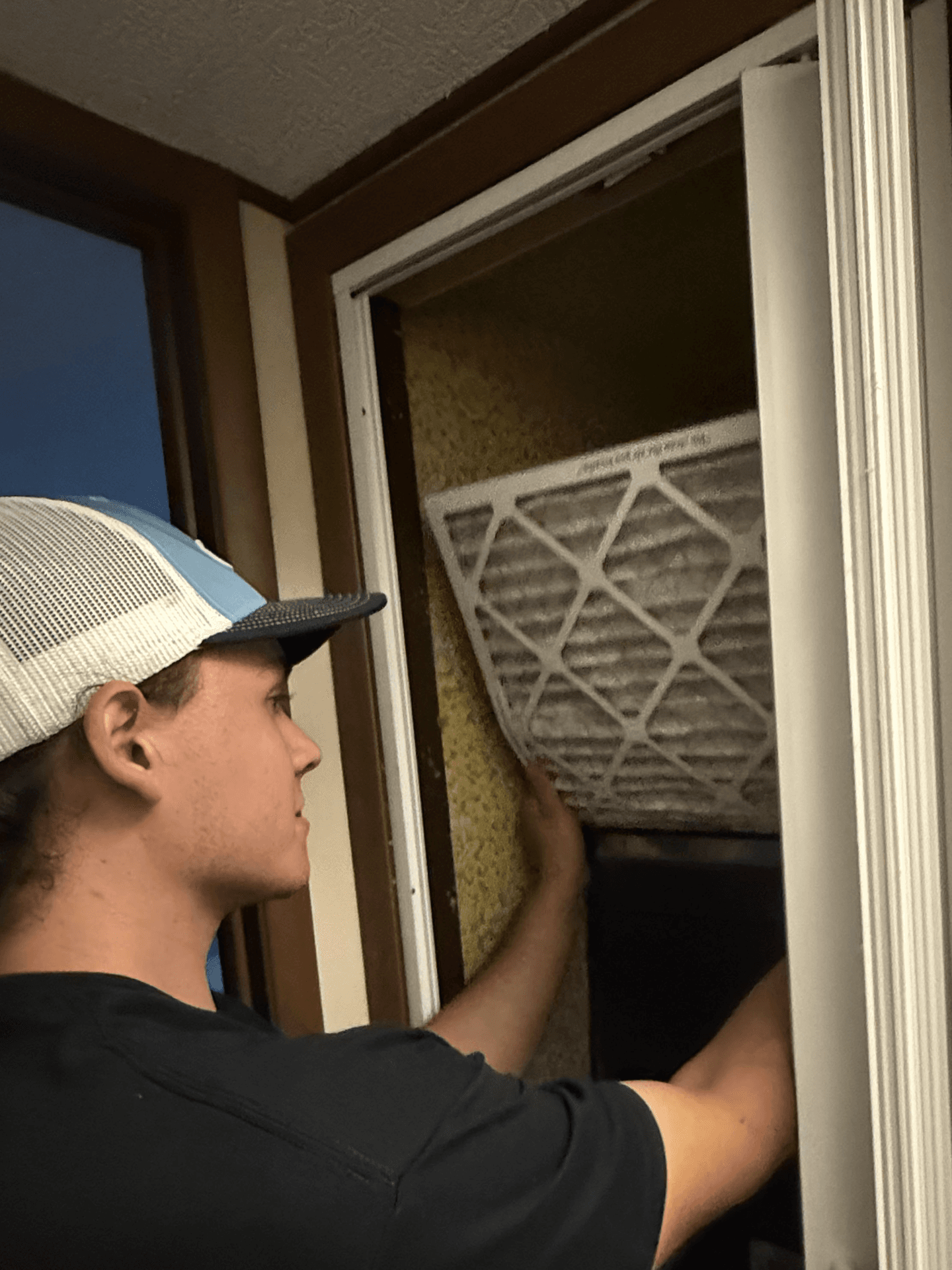 Technician installing a fresh pleated HVAC filter